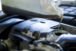 Mechanic pouring oil lubricant into the car engine